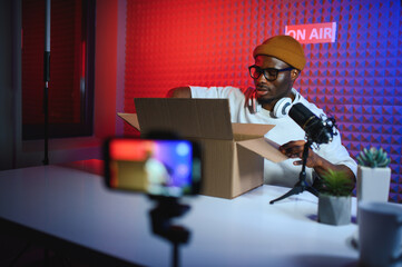 african american vlogger using smartphone to film podcast in studio. blogger with mobile phone,...