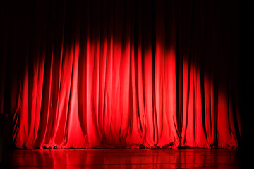 Closed red curtains on theater stage with spotlight