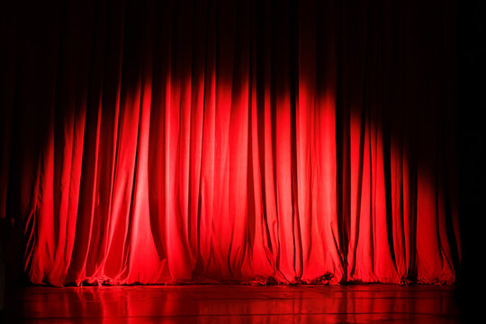 Closed red curtains on theater stage with spotlight