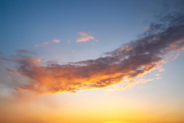 Sunset sky with layered clouds in various shades of blue, gray, and gold. A mesmerizing display of...