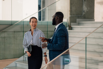 Businesspeople walking and talking on stairs in modern office building