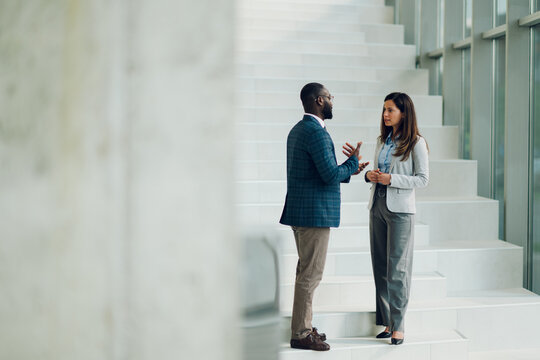 Business colleagues discussing strategy on modern office stairs