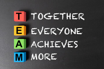 Colorful blocks pieces with Team acronym means together everyone achieves more on chalkboard