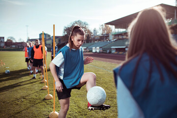 Female soccer players training with passing drills on outdoor field