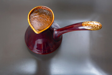 Stylish close-up of a cezve with aromatic Turkish coffee on a gray surface. Ideal for modern cafe...