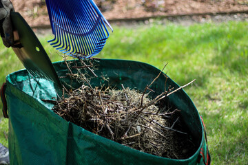 a person using a leaf scoop and rake to collect leaves and debris and put it in a large bag. yard...