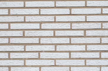 Wall made of narrow white ceramic bricks, textured and uniform surface, ideal for a variety of design and architectural projects,