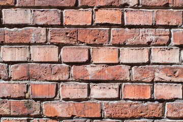 Fototapeta premium Dark brown brick wall in contrasting sunlight highlights its rough textured surface and chaotic masonry, old historical building,