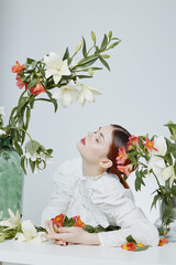 A woman in a white blouse surrounded by vibrant flowers, exhibiting a serene expression, perfect...