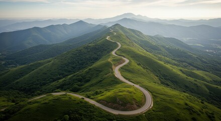 Mountain road represents journey and adventure, with green hills and distant peaks