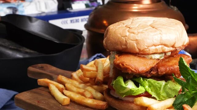 The fried fish sandwich boasts a crispy fillet tucked into a soft bun, layered with fresh tomato, crisp lettuce, and creamy tartar sauce for a delightful balance of textures and tangy flavors.