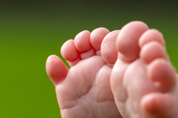 Super macro shot of a baby's toes and feet on a sunny day in the park. Natural green background.
