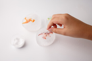 Partially melted frozen eggs revealing dinosaur toys inside translucent ice, key moment in sensory...