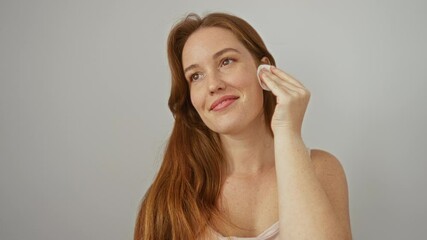 Woman cleansing skin with cotton pad on white background showing gentle skincare routine with natural products for healthy complexion.