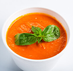 Spanish cuisine hot food delivery - tomato diet cream soup gazpacho isolated closeup in white plastic plate