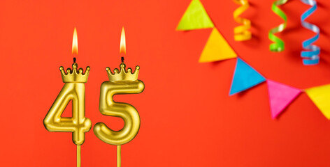 Number 45 candle - Birthday celebration on an orange background with pennants