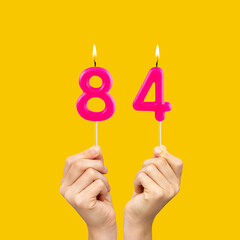 Birthday number 84 - Hands holding fuchsia colored candles