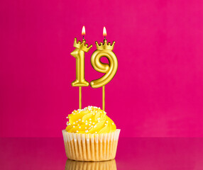 Yellow birthday cupcake with a number 19 candle - Birthday card on a pink background