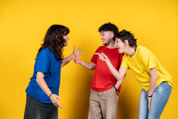 Young people gossiping and pointing at someone on yellow background