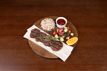 Istanbul lefte, Turkish rice with meat and adjika, mixed salad and shish kebab made from local minced meat on the table in the restaurant on a wooden stand