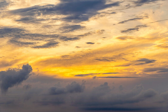 Sunlight between clouds heavy with rain, during sunset (golden hour). Abstract landscape formed by clouds and sunlight