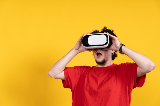 Young man exploring virtual reality with headset on yellow background