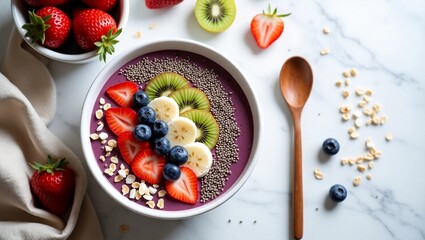 Top-down flatlay of a vibrant smoothie bowl on a white marble background. The bowl is filled with purple acai smoothie and beautifully topped with sliced strawberries, blueberries, kiwi, banana