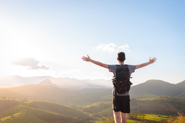 Young man with open arms at golden sunset, embracing mental wellness and relaxation through solo...