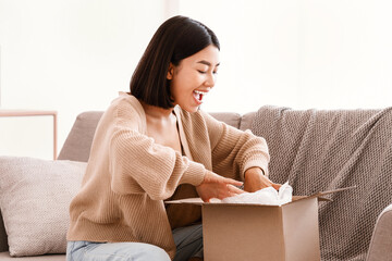 Quick Delivery Service Concept. Happy asian lady received package, unpacking cardboard box, sitting...