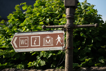 Tourism sign indicating direction to museum, tourist information and toilets. Arrow pointing to the...