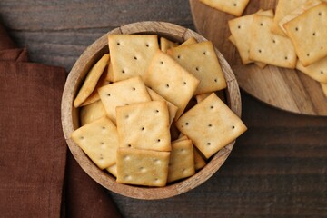 Tasty salty crackers on wooden table, top view