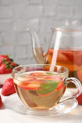 Aromatic fruit tea, strawberries and mint on white table, closeup