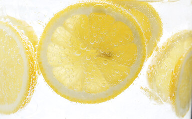 Refreshing soda water with slices of lemon in glass on white background, closeup