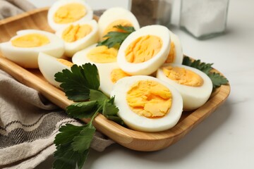 Boiled eggs and parsley on white marble table, closeup