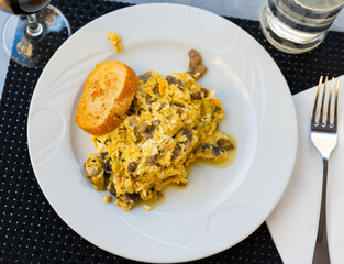 Omelet. Tasty mushroom omelet on porcelain plate on table served with fresh bread. Breakfast idea.
