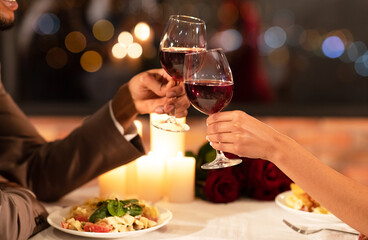 Romantic Dinner Concept. Black Couple's Hands Clinking Glasses Of Red Wine Dating Sitting In Restaurant. Closeup, Cropped