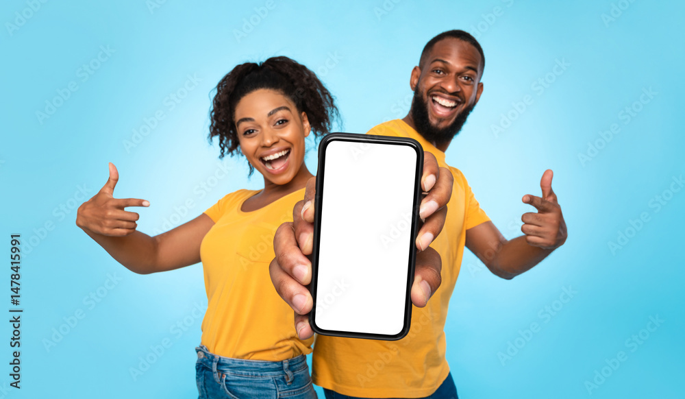 Poster use this new mobile app. joyful african american couple pointing at smartphone with empty white scre