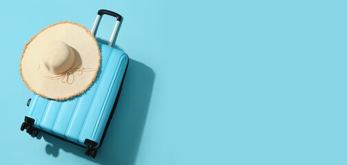 Suitcase and hat on light blue background with space for text. Tourism concept