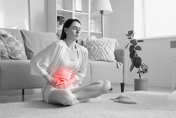 Young woman suffering from severe abdominal pain at home