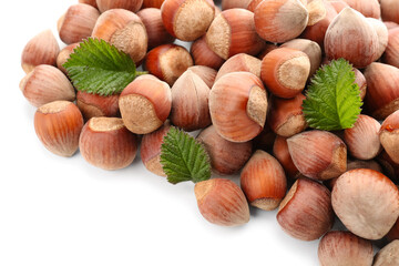 Shelled hazelnuts with leaves on white background