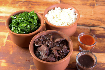 Brazilian food feijoada made with beans, pork, bacon, sausage with cabbage, rice, salad, spices and pepper. isolated on white background