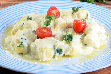 delicious gnocchi pasta in white sauce with parmesan cheese, tomato, basil, herbs, healthy food from Italian and French cuisine