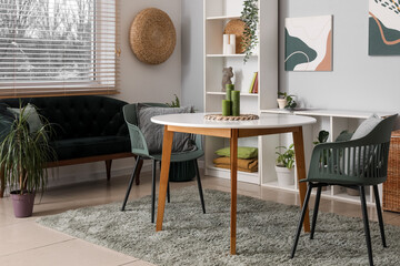 Beautiful living room with table, black cozy sofa and shelving unit