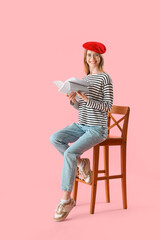 Female author with paper sheets sitting on pink background