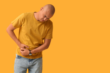 Young man with appendicitis on yellow background