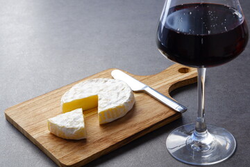 Glass of Wine with camembert cheese on the wooden cutting board on the table