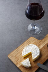 Glass of Wine with camembert cheese on the wooden cutting board on the table