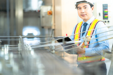 Focused engineer inspecting industrial equipment, wearing safety gear and taking notes. Precision, quality control, and manufacturing process concept.