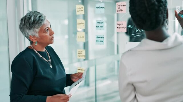 Business people, glass wall and brainstorming in office, planning or meeting for problem solving. Employees, corporate report or thinking in workplace, discussion or sticky notes with ideas or choice