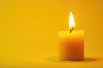 Close-up of burning yellow candle on yellow backdrop, background, celebration, yellow flame